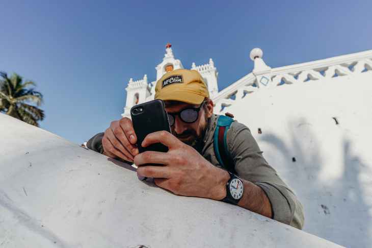 man in gray jacket holding black smartphone